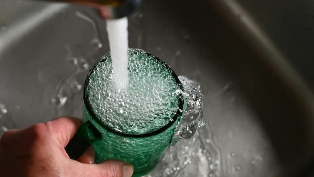 serving tap water onto a glass. Water quality. Common water contaminants. 